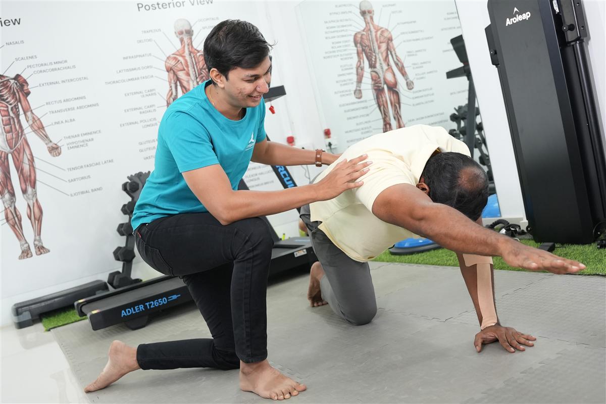 PhysioShine therapist guiding a patient through a low back mobility exercise