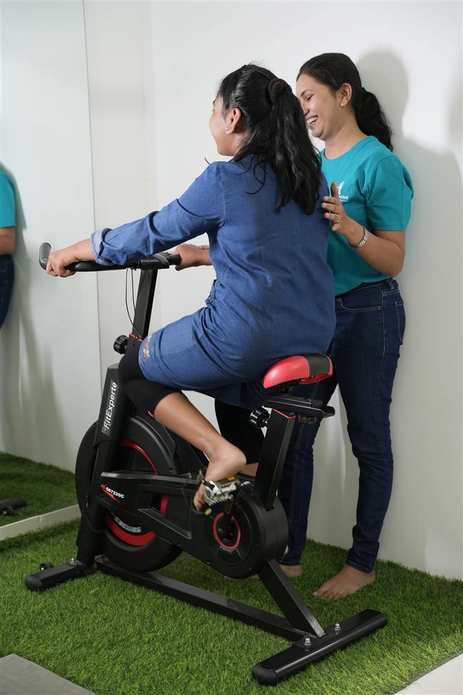 Therapist guiding a child on an exercise bike at the PhysioShine rehabilitation centre